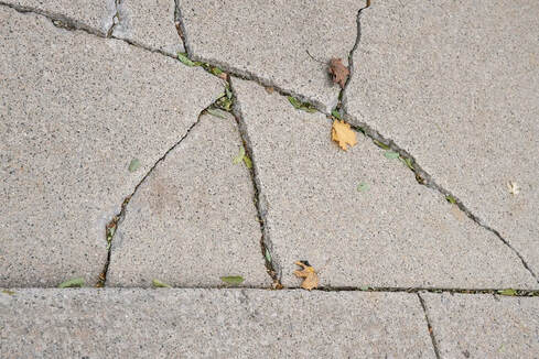 Close up of concrete driveway with a multiple cracks